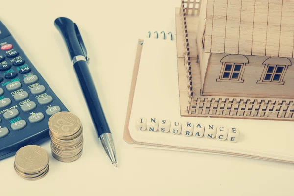 Concept of housing purchase and insurance. Office desk table with supplies top view. Calculator. golden coins, pen, notepad, model house, wooden block word — Stock Photo, Image