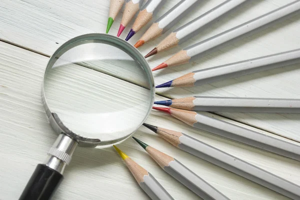 Magnifying glass, pencils on wooden table. Copy space for text. Search idea concept — Stock Photo, Image