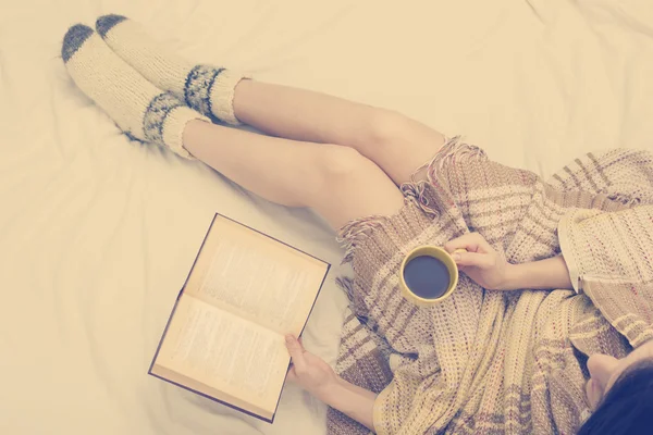 Mulher na cama com livro velho e xícara de café nas mãos, ponto de vista superior. Copiar espaço para texto. Foto suave — Fotografia de Stock