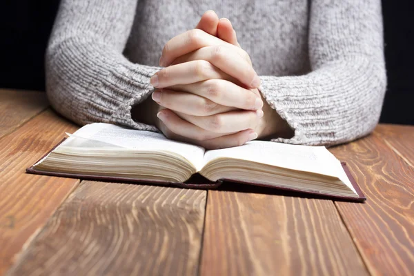 Mulher mãos orando com uma bíblia no escuro sobre mesa de madeira — Fotografia de Stock