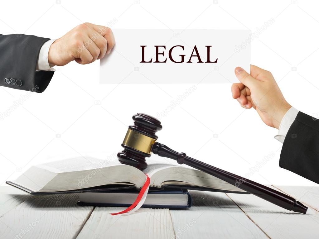 Law book and wooden judges gavel on table in a courtroom or law enforcement office. Lawyer Hands holding business card with text Legal