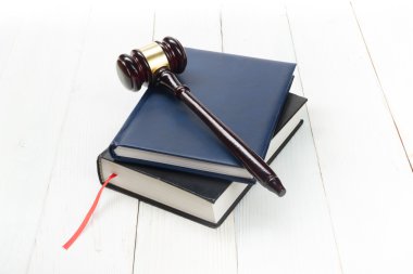 Bir mahkeme salonunda masada ahşap hakimler tokmak ile açık kanun kitabı