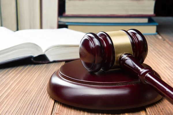 Libro de la ley con jueces de madera martillo en la mesa en una sala de tribunal o la oficina de aplicación de la ley . — Foto de Stock