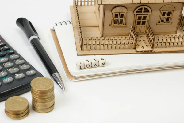 Concepto de compra y seguro de vivienda. Mesa de escritorio de oficina con vista superior suministros. Calculadora. monedas de oro, pluma, bloc de notas, casa modelo verde, palabra de bloque de madera — Foto de Stock