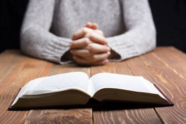 İçinde karanlık bir İncil ile ahşap masa üzerinde dua eller kadın