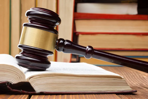 Law book with wooden judges gavel on table in a courtroom or law enforcement office.