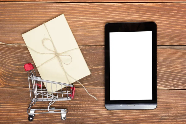 Concetto di shopping online: carrello vuoto, laptop e tablet, confezione regalo su sfondo rustico in legno — Foto Stock