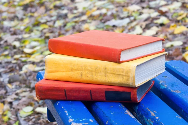 Stack di libro hardback sdraiato su una panchina al tramonto parco sfondo natura offuscata . — Foto Stock