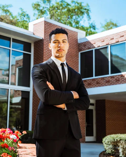 Genç, kendine güvenen yakışıklı işadamı ya da üniversite öğrencisi dışarıda bir tuğla binanın karşısında durup kameraların karşısına bakıyor.