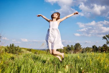 Beyaz elbiseli kız tarlada yürüyor.