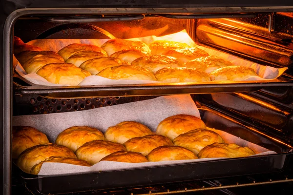 Hot oven with golden buns — Stock Photo, Image