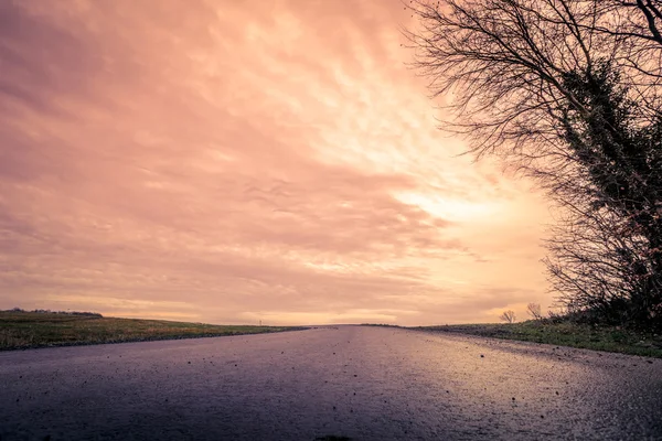 Estrada feita de asfalto ao pôr do sol — Fotografia de Stock