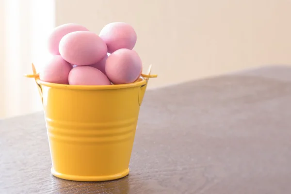 Balde amarelo com ovos de Páscoa violeta — Fotografia de Stock