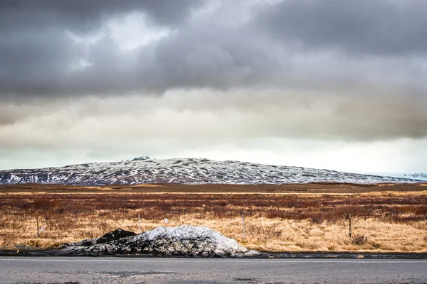 Neve por uma estrada em cenário dramático — Fotografia de Stock
