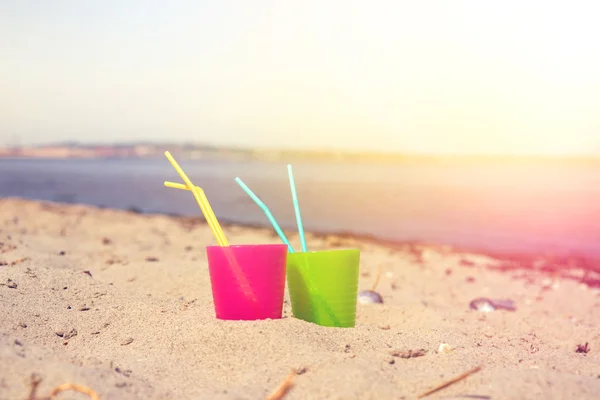 Kleurrijke drinken cups in het zand — Stockfoto