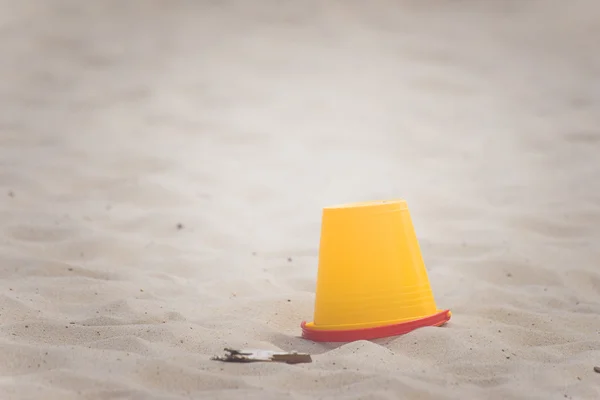 Balde amarelo em uma praia — Fotografia de Stock