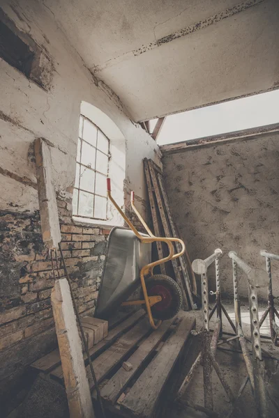 Wheelbarrow in a warn barn — Stock Photo, Image