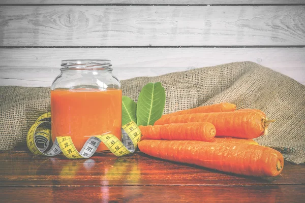 Tarro con jugo de zanahoria en una mesa de madera — Foto de Stock