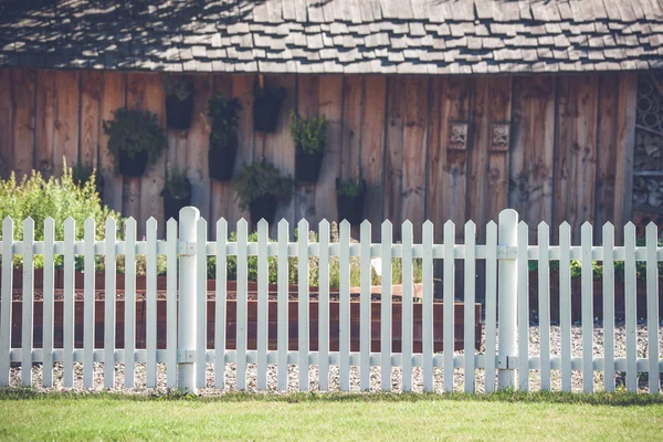 Białego szpica ogrodzenia z przodu af drewniana szopa — Zdjęcie stockowe