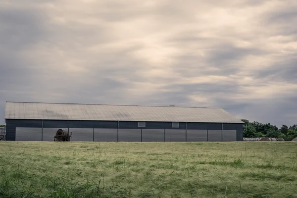 Landbouw schuur op een groen veld — Stockfoto