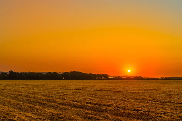 Nascer do sol sobre um campo rural — Fotografia de Stock