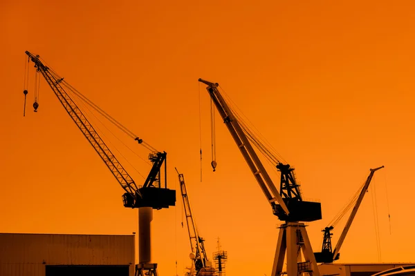 Silhuetas de guindaste em um porto de navegação — Fotografia de Stock