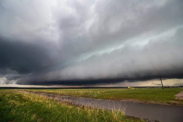 大平原の嵐の最先端には棚雲が近づき 前景には満杯の運河がある — ストック写真