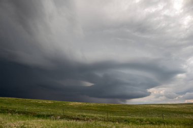 An anticyclonic supercell thunderstorm hangs in the sky over the high plains, its updraft spinning with a striated appearance.