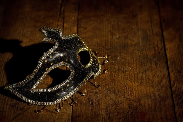 Máscara preta e dourada na mesa de madeira — Fotografia de Stock