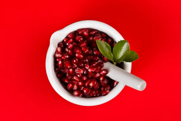 Grenadine seeds in a mortar on red — Stock Photo, Image