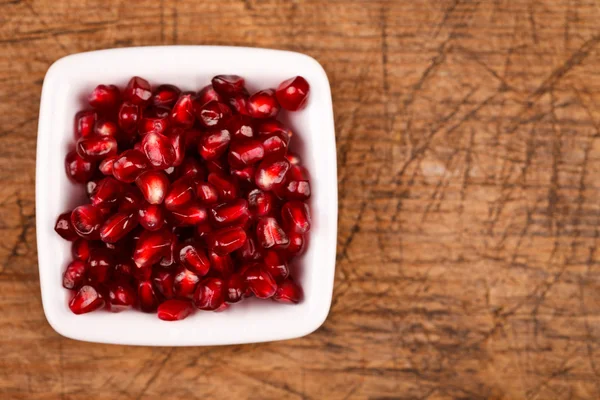 Red grenadine seeds on white plate — Stock Photo, Image