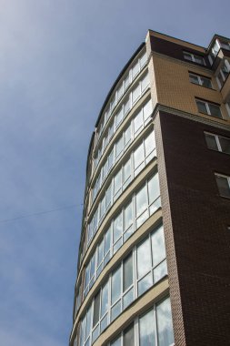 Mavi gökyüzünün arka planında çok katlı bir bina.