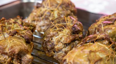 Fırında pişirilmiş et yemeği, arka planda baharat ve biberiye ile süslenmiş.