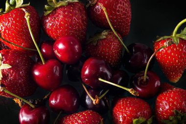 Sağlam bir arka planda olgun çilek ve kiraz, sağlıklı vejetaryen yiyecekler. Güzel
