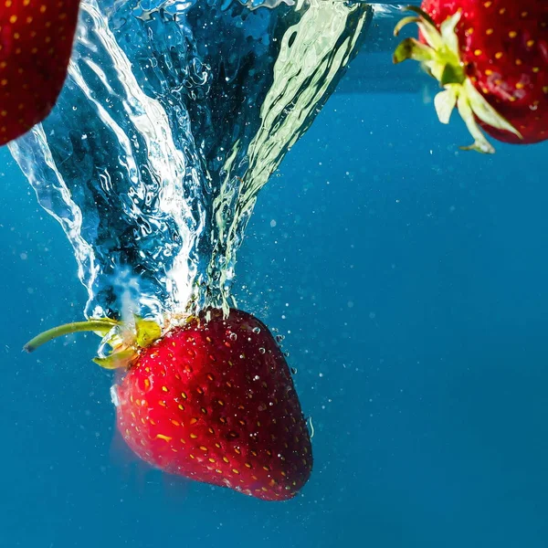 stock image ripe strawberries fall into the water lifting splashes and air bubbles