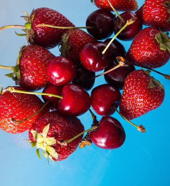 Sağlam bir arka planda olgun çilek ve kiraz, sağlıklı vejetaryen yiyecekler. Güzel