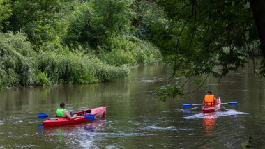 Küçük bir nehirde kano ve kürek çeken bir gezgin..