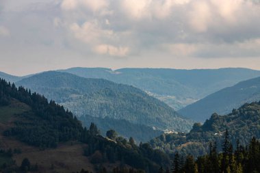 Ukrayna Karpatları 'nın dağ yamaçlarında. Dağın tepeleri ve ormanlar mavi gökyüzünün arka planında.