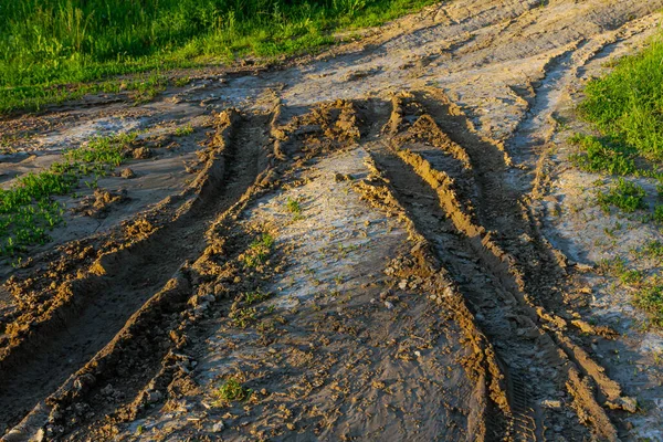Çamur yolu, altın saat boyunca kırsal alanda lastik izleri ile işaretlenmiş. Bu da doğanın araç hareketinin dokusunu ve etkilerini gözler önüne seriyor..