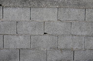 Beton bir duvar, malzemenin dokusunu ve Arnavutluk 'un kentsel bölgelerinde yaygın olan mimari tarzını gösteren pürüzlü, yıpranmış bloklardan oluşan bir desen sergiliyor..