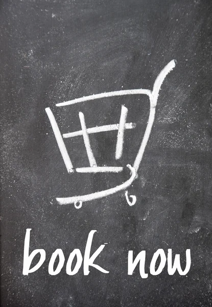 Book now text and shopping cart sign on blackboard — Stock Photo, Image