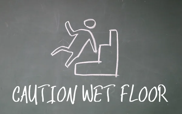 Caution wet floor sign on blackboard — Stock Photo, Image
