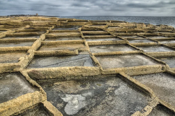 Malta Salina de la isla tallada en el acantilado de piedra caliza — Foto de Stock