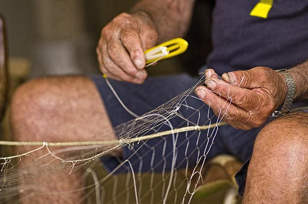 Vecchio villaggio di pescatori di Trani intento a riparare le reti da pesca — Foto Stock