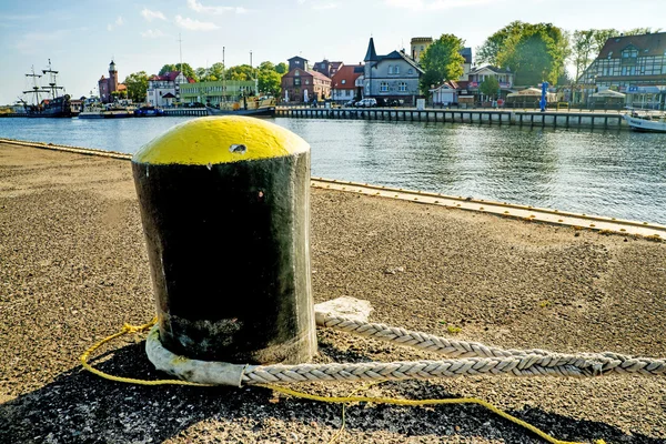 Bolardo en un puerto con barco de vela y faro — Foto de Stock