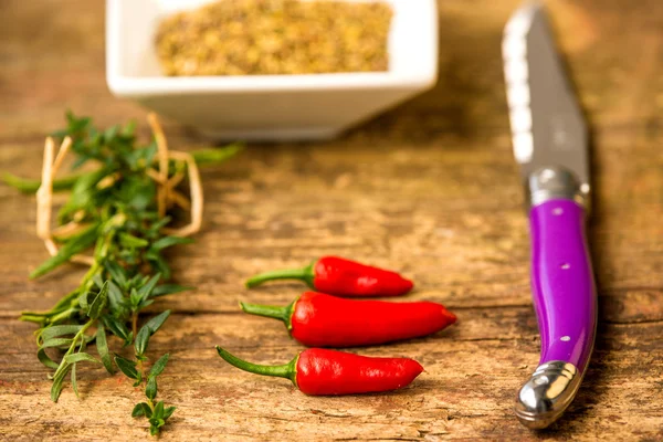 Rijpe, rode Chili vruchten met kruiden en mes — Stockfoto