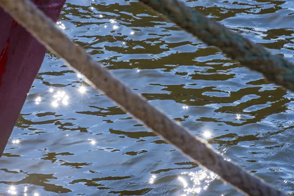 Linha de amarração de um arrastão em retroiluminação com reflexos de água — Fotografia de Stock