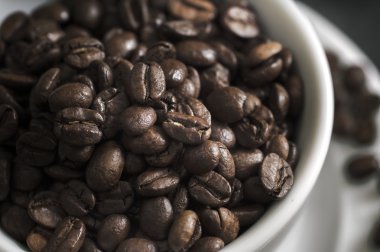 Kahve fincanı kahve çekirdekleri ile taşan