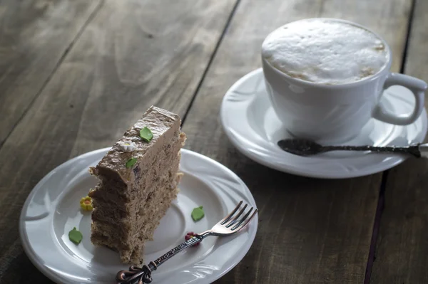 Bolo de chocolate no prato branco com uma xícara de café — Fotografia de Stock