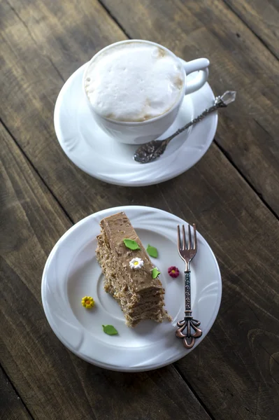 Bolo de chocolate no prato branco com uma xícara de café — Fotografia de Stock